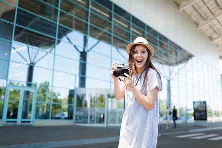 年轻的惊喜快乐的旅行妇女在帽子持有复古复古照片相机在国际机场。在周末外出旅行的女乘客。航空飞行概念