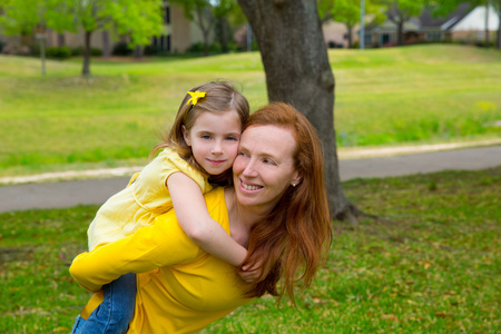 女儿和母亲背驮式微笑在公园户外