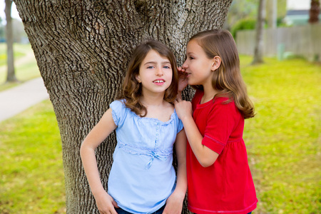 孩子的朋友女孩耳语耳玩公园树中