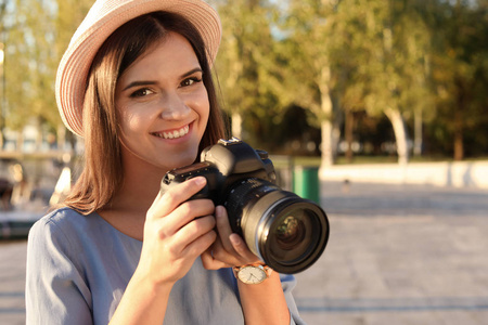 年轻的女摄影师与专业相机在街上。文本空间