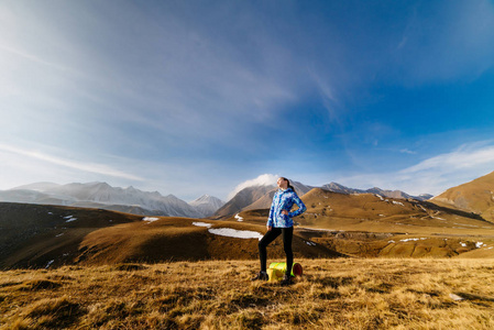 活跃的年轻女孩穿着蓝色夹克穿过高加索山脉, 享受大自然
