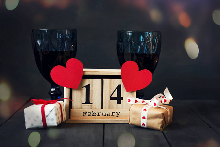两杯酒, 一份纸心, 一份日历, 日期在 2月14日, 一个礼物。在黑暗的木制背景下复制空间。情人节
