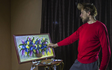 一个穿着红毛衣的大胡子画家画了一幅艺术画笔在画室里更的花朵静物