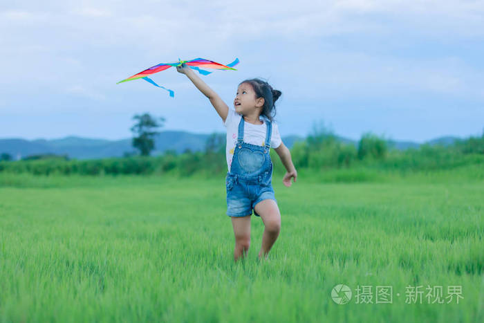 亚洲儿童女孩一起运行和快乐中汇总的草地上放风筝