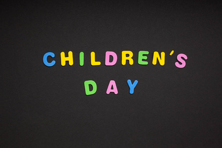 创意五颜六色的文字, 由塑料字母儿童节写在黑色的纸背景与复制空间。节日留言概念, 庆典卡模板