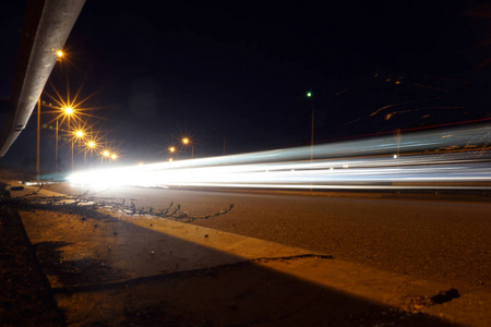 空沥青路面在夜间与光线小径背景。夜间城市场景与车光小径在隧道。长时间曝光