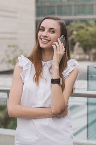 年轻的欧洲女性通过手机与快乐和微笑的脸交谈。成功的办公室工人或女企业家