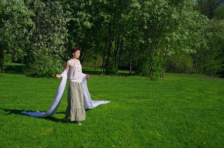 春天的一天，年轻的东方女人走在绿色的草地上