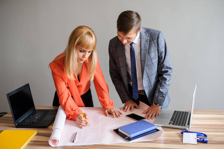 一个商业妇女和男人在木办公桌上看着纸上的项目, 使用钢笔和罗盘