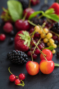 混合浆果在黑暗背景与选定的焦点。草莓, 覆盆子黑莓, 樱桃, 红色和黄色洋流。健康的生活和营养的食物概念