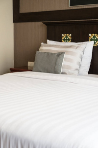 舒适的枕头在床上与灯装饰在旅馆卧室内部