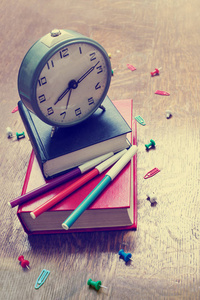 不同学校用品的特写镜头在木桌上的钟表和书籍