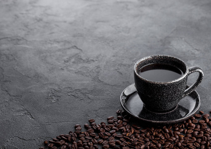 黑色咖啡杯与飞碟和新鲜咖啡豆在黑石厨房表背景