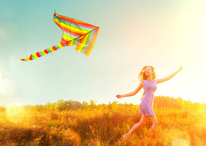 女孩在短的衣裳奔跑与飞行五颜六色的风筝