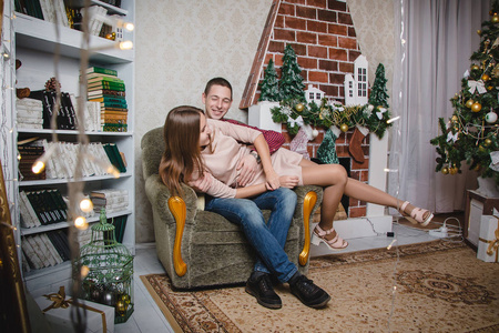 年轻夫妇在圣诞和新年装饰的房间里庆祝圣诞节