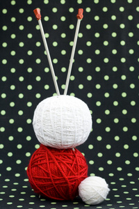 红色和白色暗背景上的针和编织毛线球