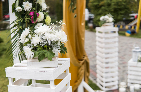 婚礼上的装饰。花木拱, 黄布, 鲜白花, 绿叶在乡间婚礼上
