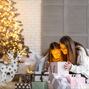 年轻的母亲和她的小女儿打开一个神奇的圣诞