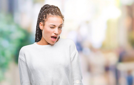 年轻的编织头发非洲裔美国人女孩穿着冬季毛衣在孤立的背景眨眼看着相机与的表情, 开朗和快乐的脸