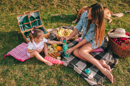 mother and daughter having a picnic in a garde