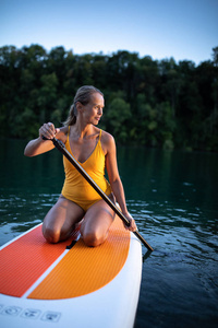 支撑桨板概念漂亮, 年轻女子桨登上一个可爱的湖在温暖的傍晚下午从水下轻拍
