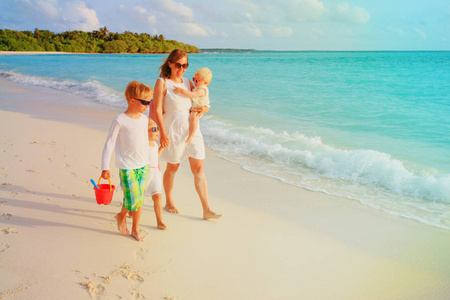 母亲与儿子和女儿在海滩漫步