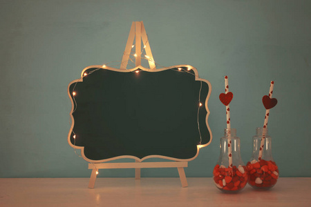 情人节浪漫的背景与塑料灯泡与心脏形状糖果和节日的灯在桌子上