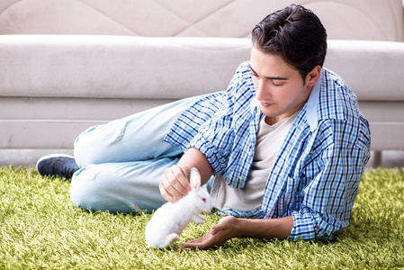 年轻男子玩宠物兔子在家