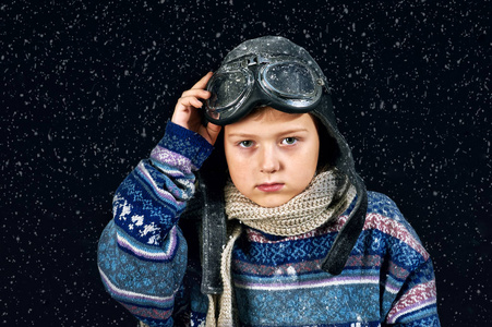 穿着暖和的毛衣和帽子的男孩的肖像。影响降雪