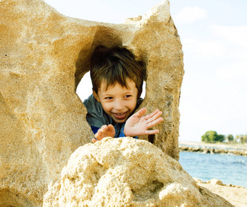 小可爱男孩在玩石头海海岸大拇指上