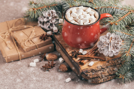 红杯热可可与棉花糖在木制切割板上的圣诞装饰品和雪效果。水平视图。复制空间