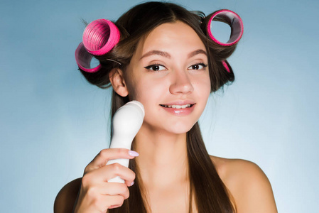 一个年轻漂亮的女孩要去参加一个聚会, 在一个夹的头上, 用电刷清除她的脸