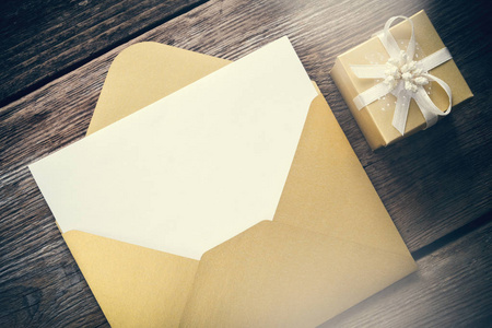 用木质板打开带空白纸和礼品盒的黄色纸信封