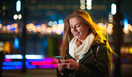 在霓虹灯的城市中使用手机的女人