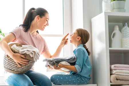 年轻漂亮的女人和孩子女孩小帮手中能开心，并微笑着做在家里洗衣