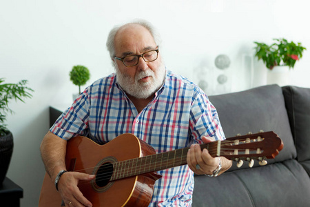 白胡子老人在家里弹吉他的画像
