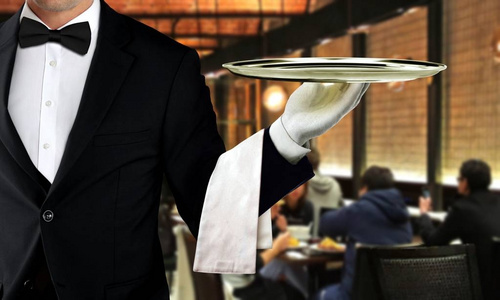 男服务员在餐馆服务在背景的人用餐