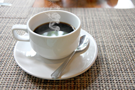热黑咖啡在桌上的白色杯子和有烟雾主要利益中心