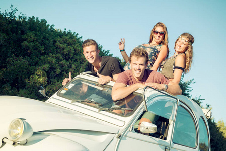 组的快乐的人，在一辆车在日落时在夏天，准备自驾旅行