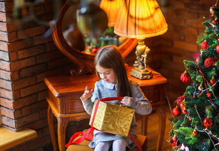 圣诞节早晨, 美丽的小女孩打开礼物坐在圣诞节的附近