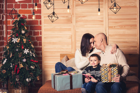 快乐的家庭坐在沙发上, 拿着糖果藤和圣诞礼物