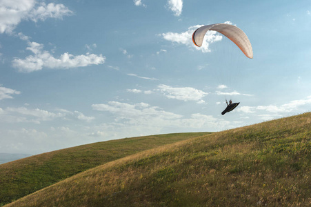 一只白色橙色的滑翔伞飞越山地地形