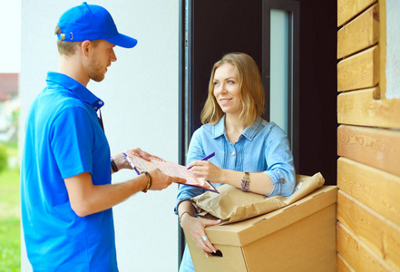 蓝色制服包裹盒送交收件人信使服务概念的交付男人微笑着。穿蓝色制服的男人微笑着交货