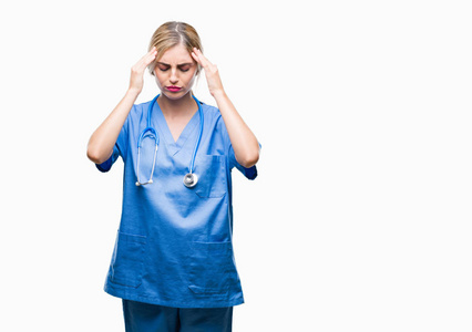 年轻美丽的金发医生外科医生护士妇女在孤立的背景与手在头上为痛苦在头由于压力。患有偏头痛