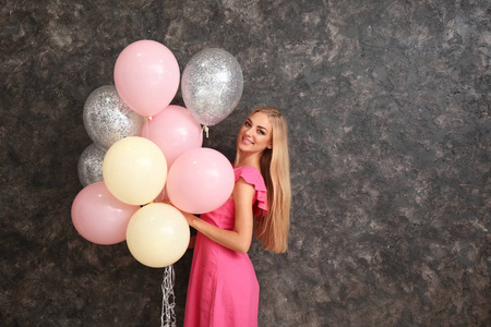 在黑暗背景的空气气球的美丽的年轻妇女