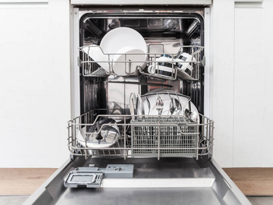 在白色的厨房里用干净的盘子打开洗碗机