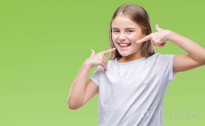 年轻美丽的女孩在孤立的背景下微笑着自信地显示和指着手指的牙齿和