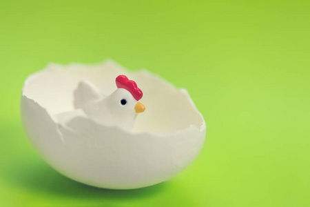 小玩具鸡在蛋壳上的绿色背景