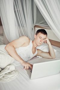 男子躺在床上与他的笔记本电脑