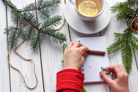 儿童之手的一张节日照片, 写在一本笔记簿, 一份茶和圣诞装饰的厝